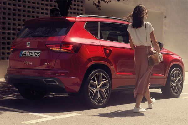 Eine Frau geht auf die Beifahrertür eines parkenden SEAT Arona zu