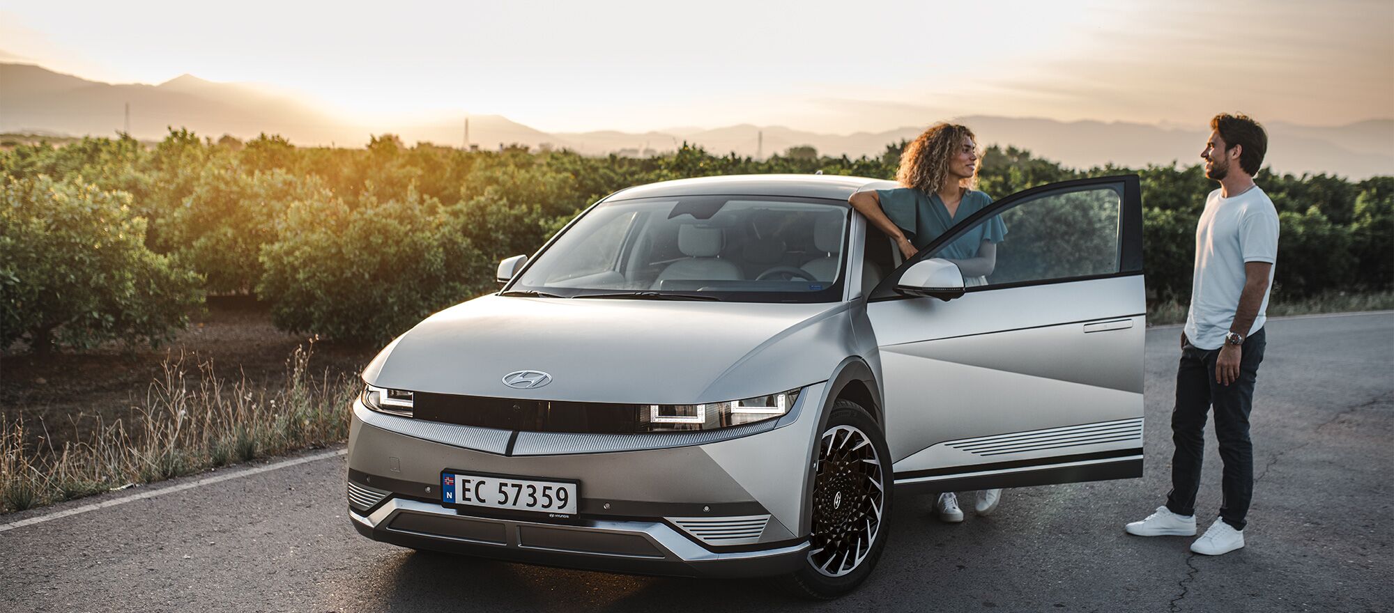 Eine Frau und ein Mann unterhalten sich neben ihrem Hyundai IONIQ 5