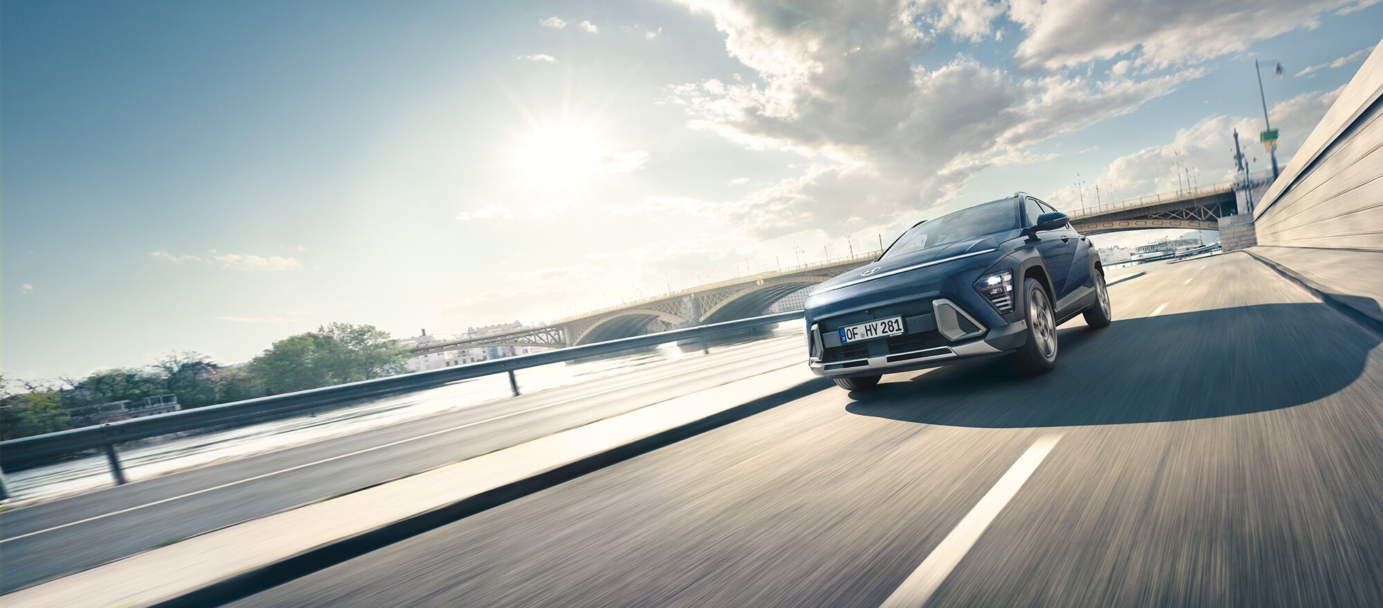 Ein Hyundai KONA fährt eine Straße neben einem Fluss entlang
