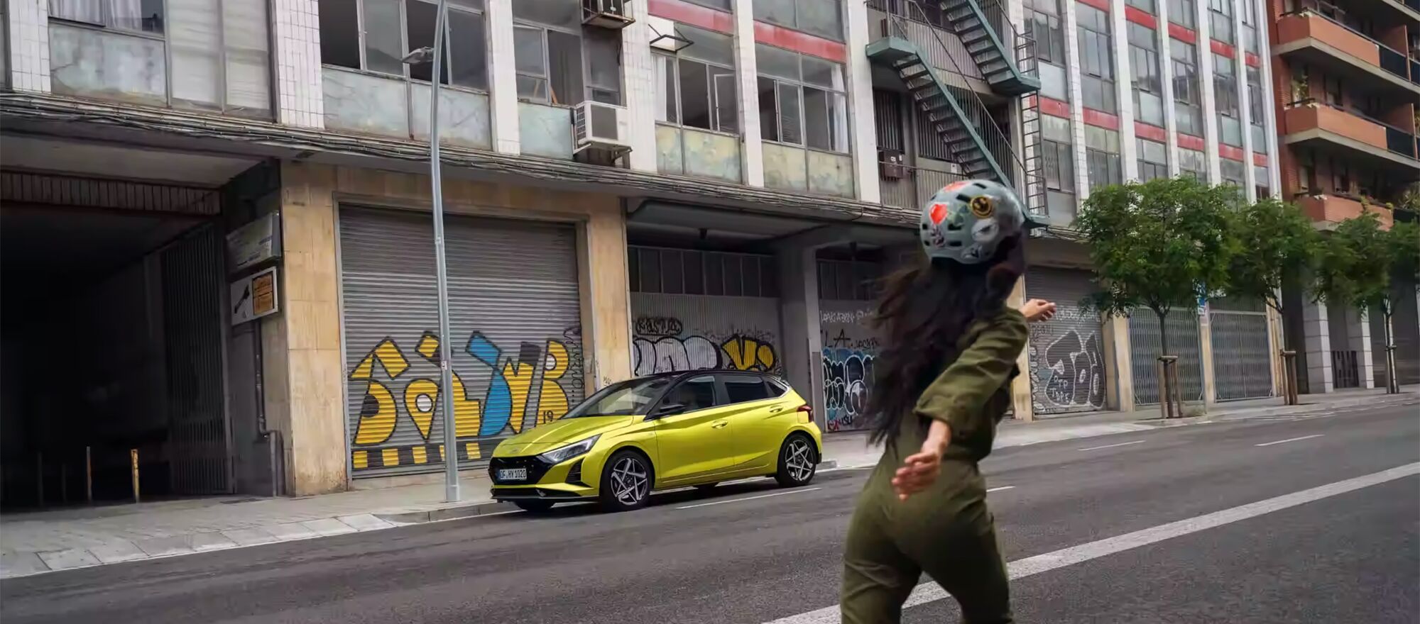 Ein gelber Hyundai i20 im Hintergrund einer skatenden Frau