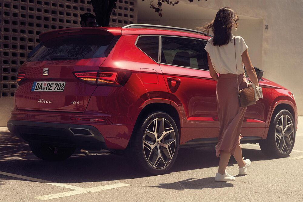 Eine Frau geht auf die Beifahrertür eines parkenden SEAT Arona zu