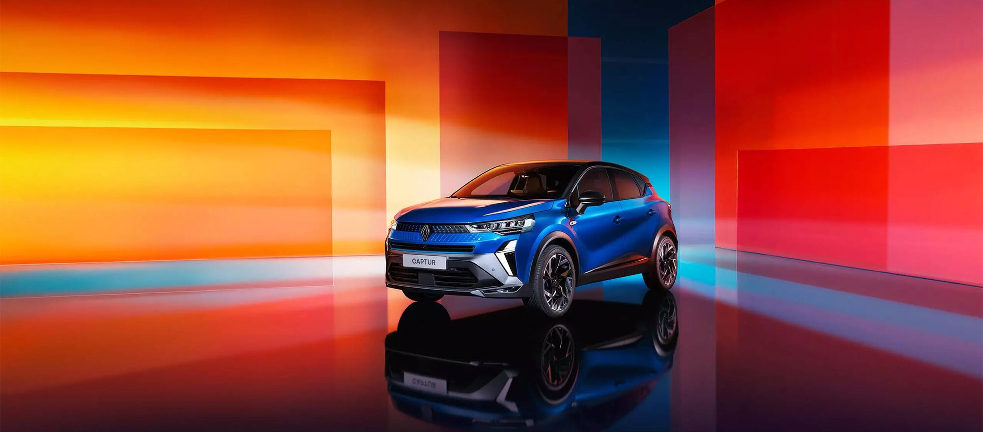Ein Renault Captur in seitlich stehend vor einer bunten Wand