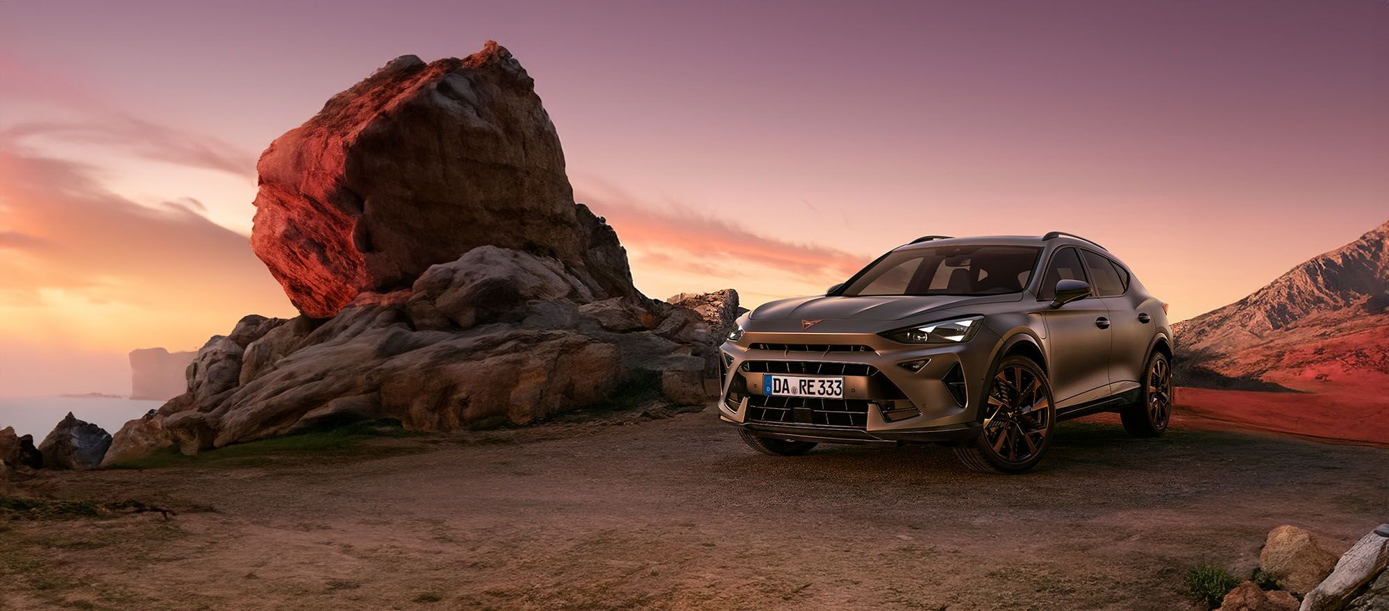CUPRA Formentor neben einem Stein beim Sonnenuntergang