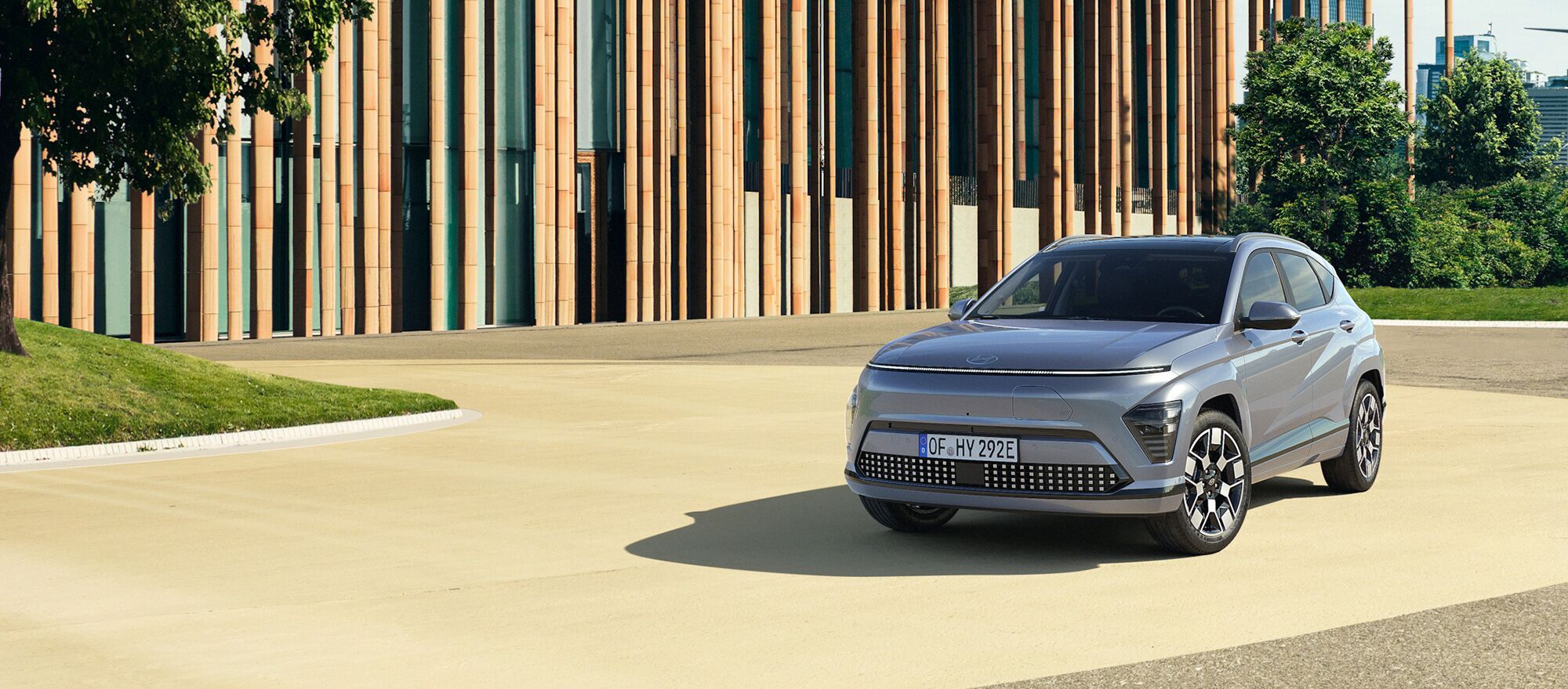 Ein Hyundai KONA Elektro parkend vor einem Park und Gebäude