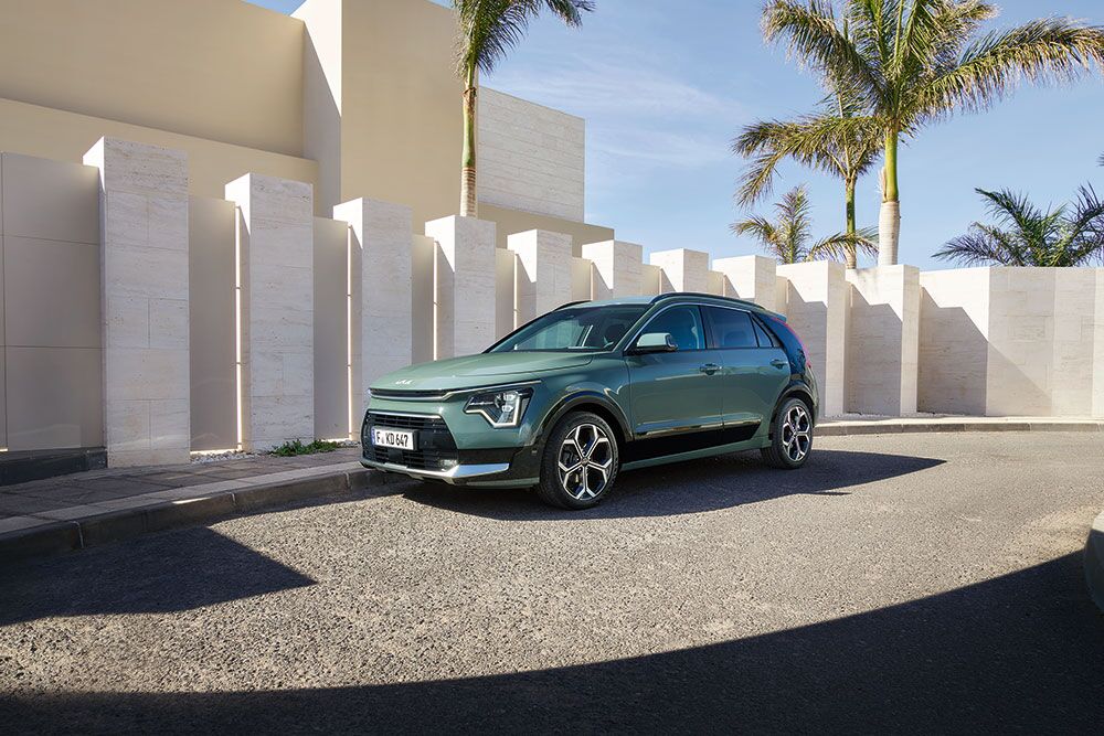 Ein parkender Kia Niro vor einem Steinzaun