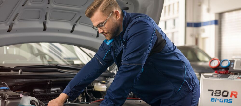 Ein KFZ Meister prüft den Zustand der Batterie eines Autos