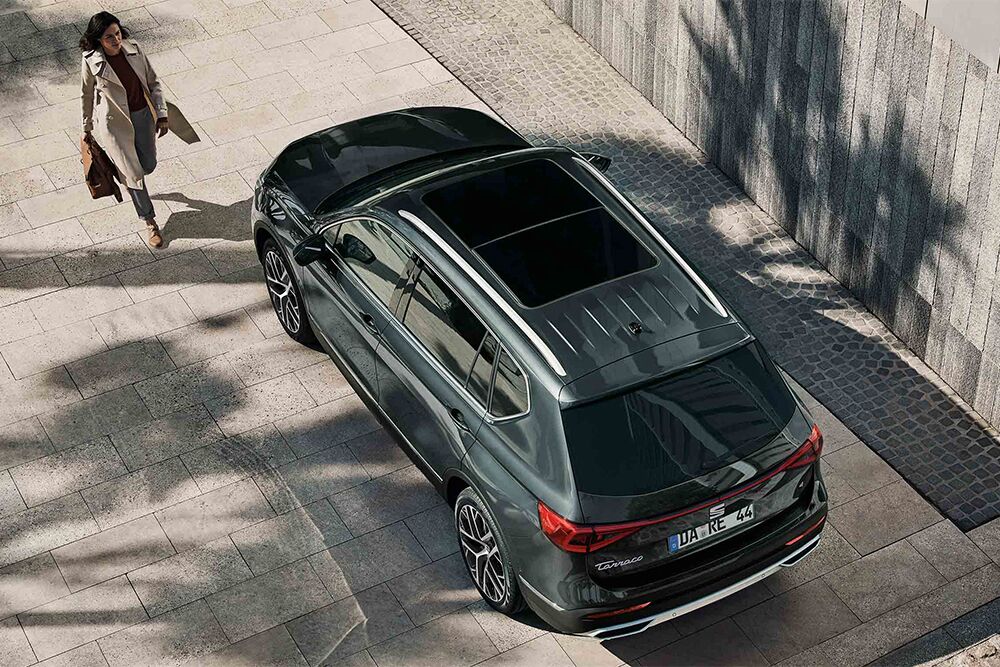 Eine Frau läuft auf die Fahrertür des SEAT Tarraco zu