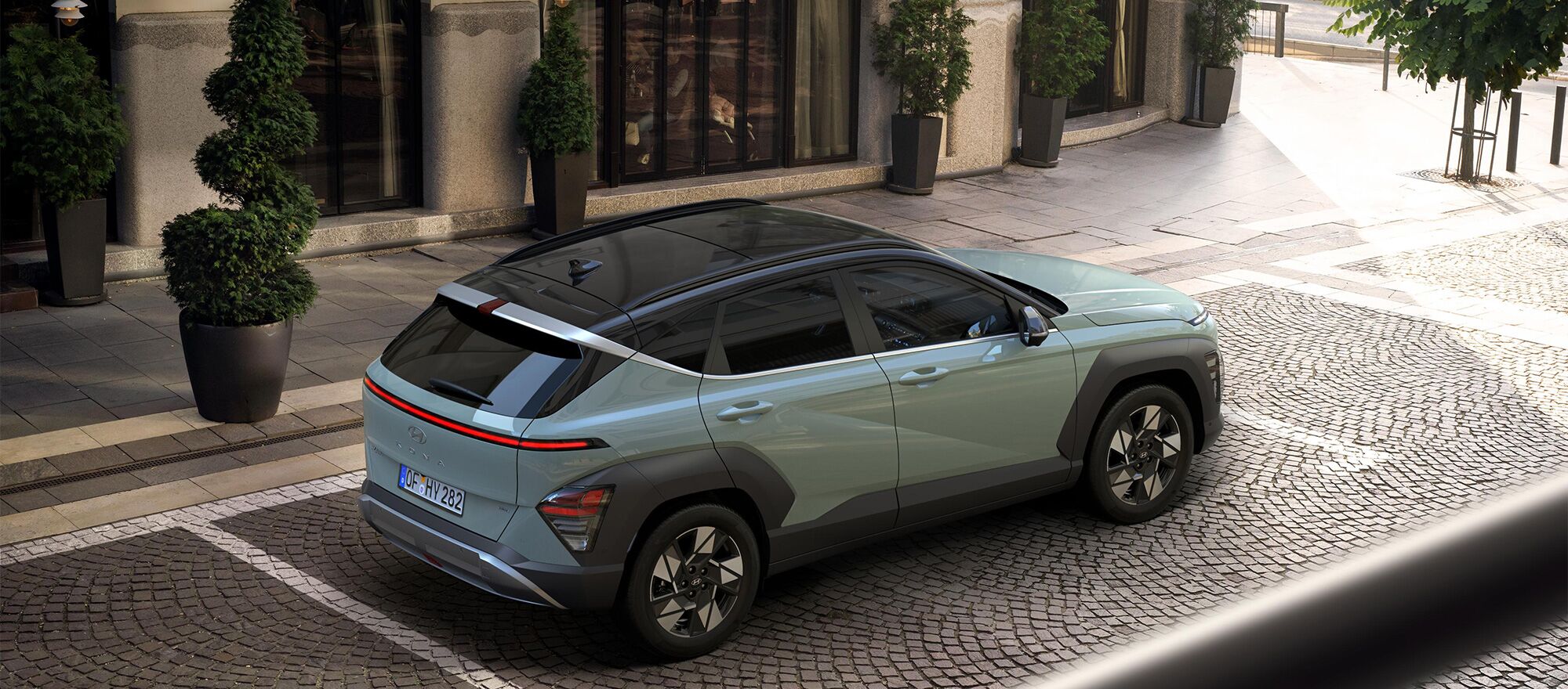 Ein prackender Hyundai KONA auf Kopfsteinpflaster vor einem Laden