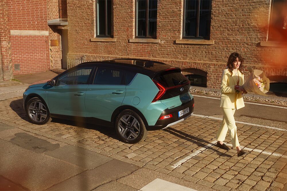 Heckansicht des Hyundai Bayon mit einer Frau daneben