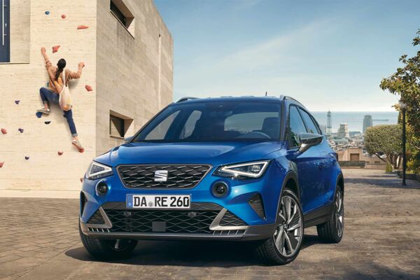 Ein SEAT Arona steht frontal vor der Kamera, im Hintergrund klettert eine Frau eine Wand hoch