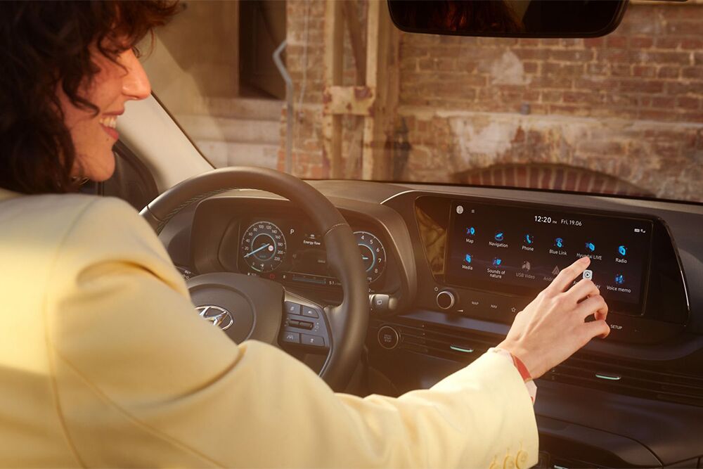 Eine Frau bedient lächelnd das Interface der Innenausstattung des Hyundai Bayon
