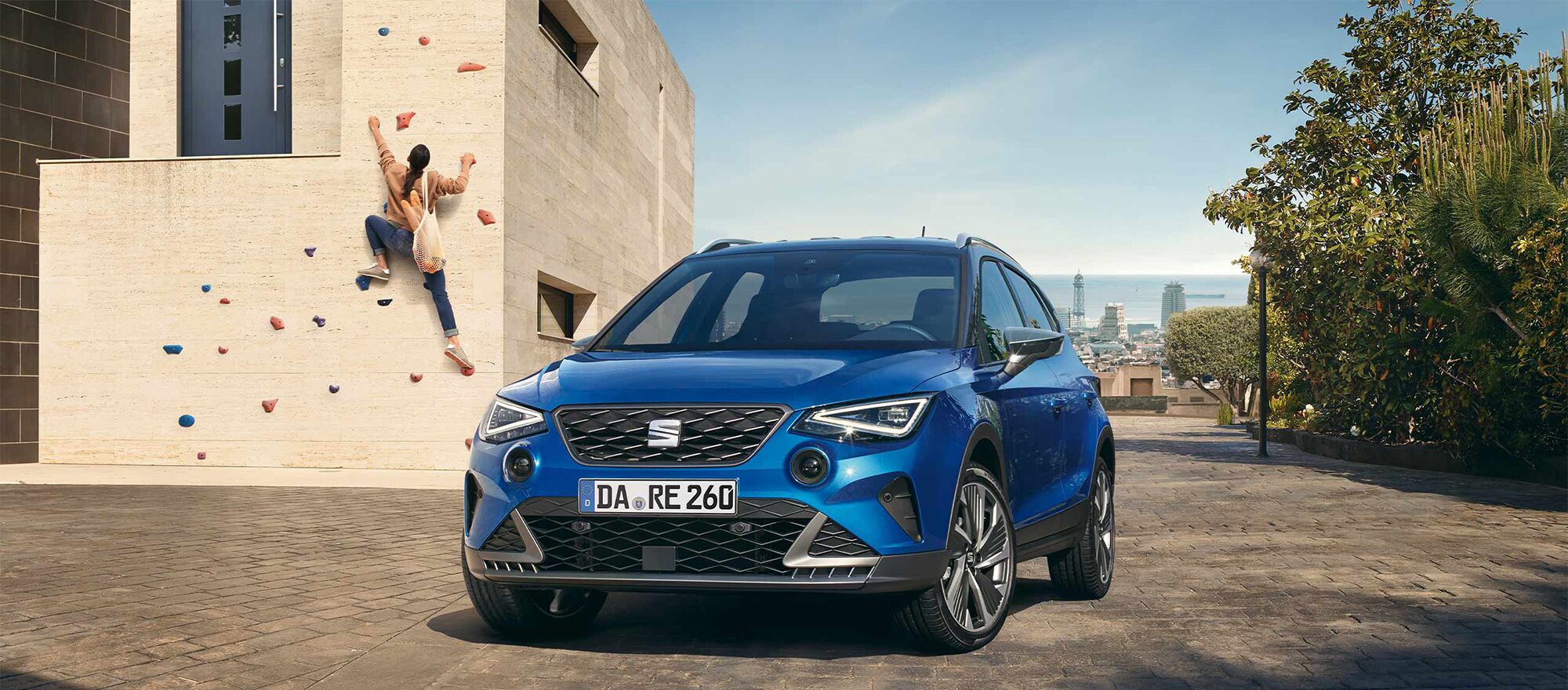 Ein SEAT Arona steht frontal vor der Kamera, im Hintergrund klettert eine Frau eine Wand hoch