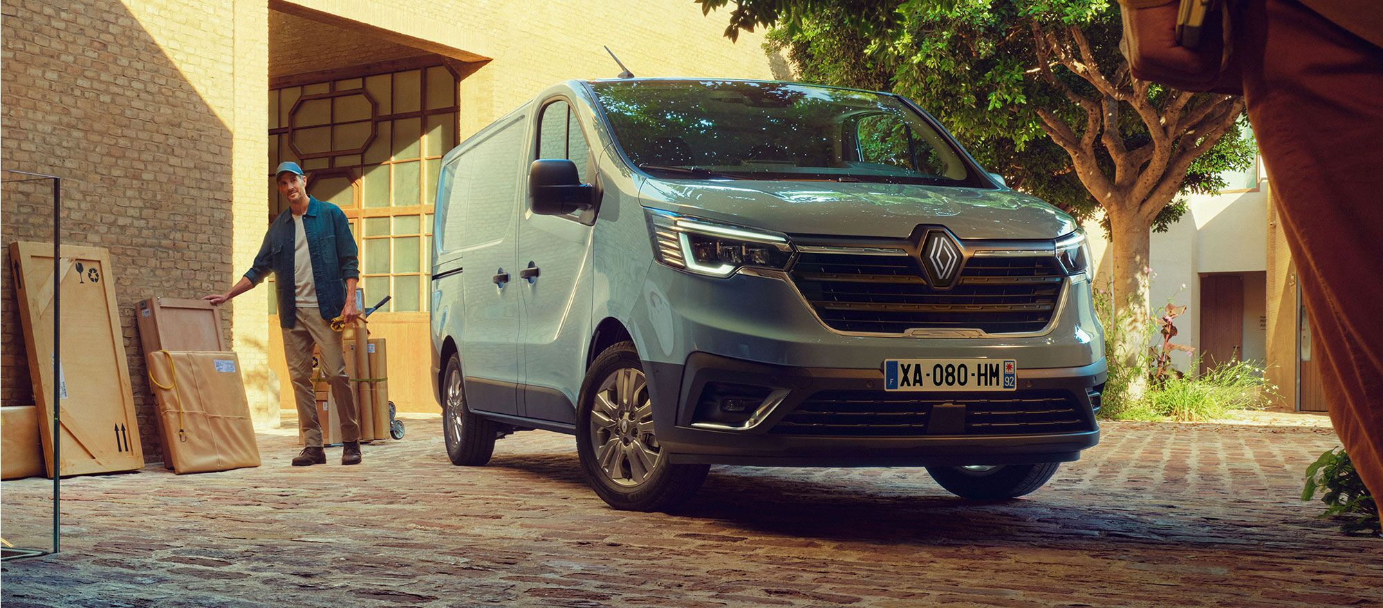 Der Renault Trafic steht vor einem Handwerker mit Paketen