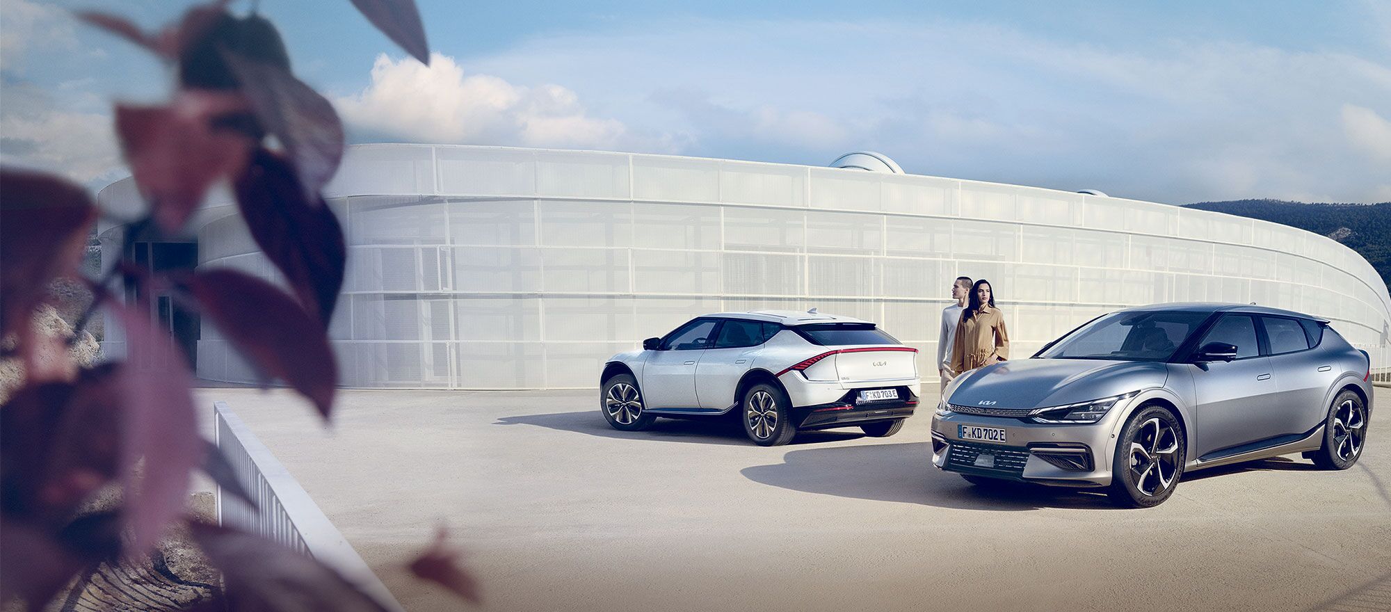 Zwei Kia EV6 stehen vor einer Beton mit zwei Menschen zwischen den Autos