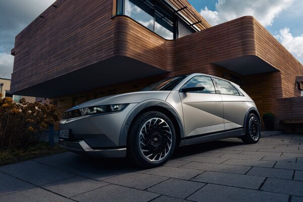 Ein parkender Hyundai IONIQ 5 vor einem Holzhaus