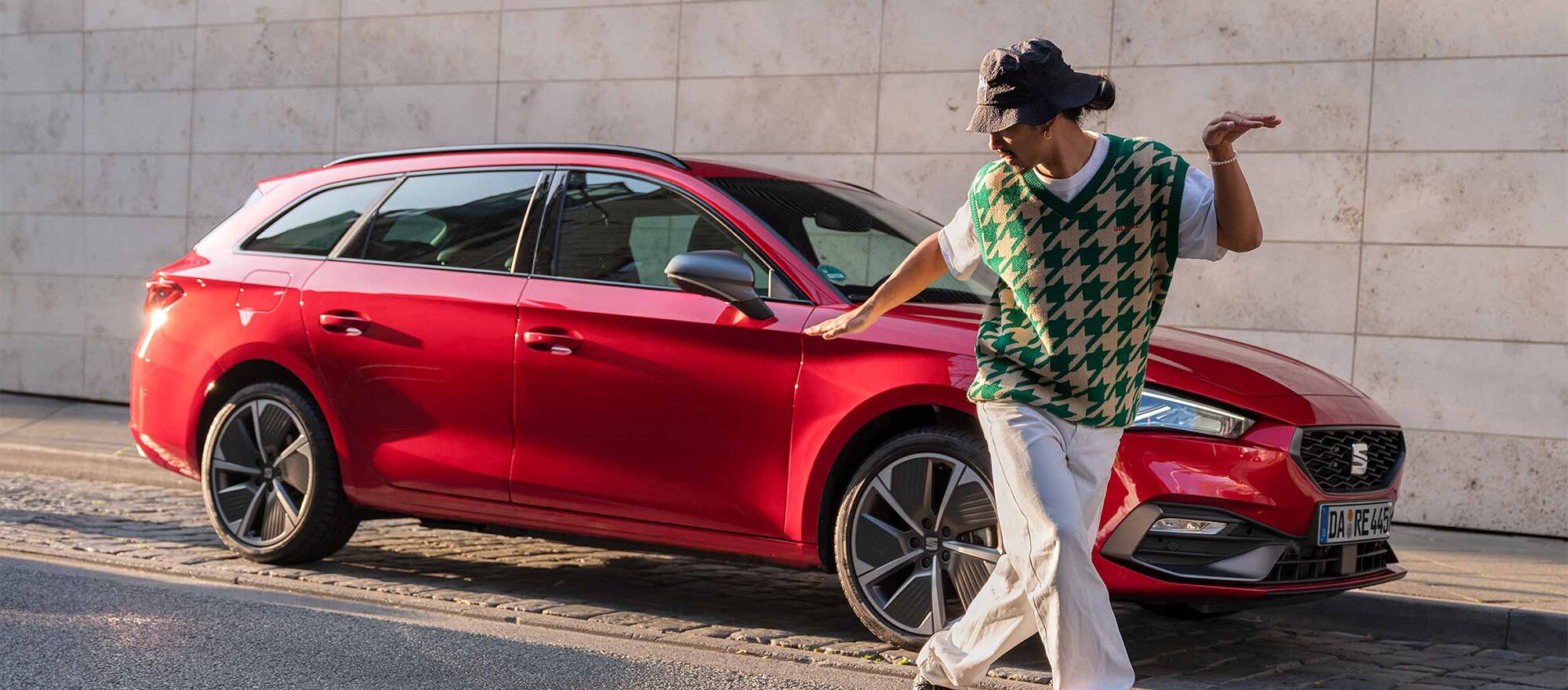 Ein Mann tanzt auf der Straße vor einem geparkten SEAT Leon Sportstourer