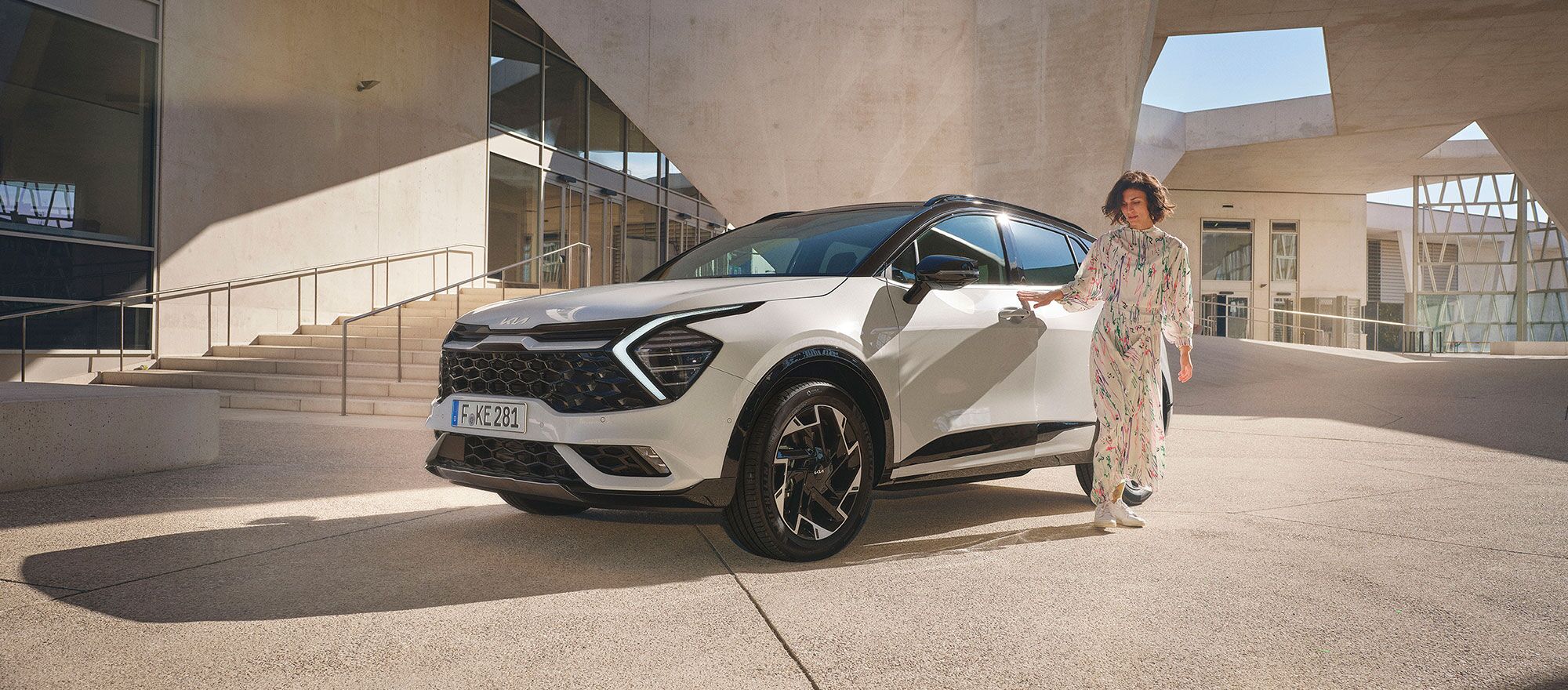 Eine Frau öffnet die Fahrertüre des Kia Sportage