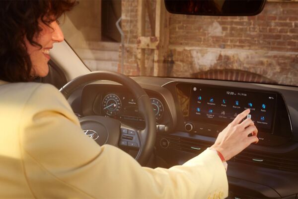 Eine Frau bedient lächelnd das Interface der Innenausstattung des Hyundai Bayon