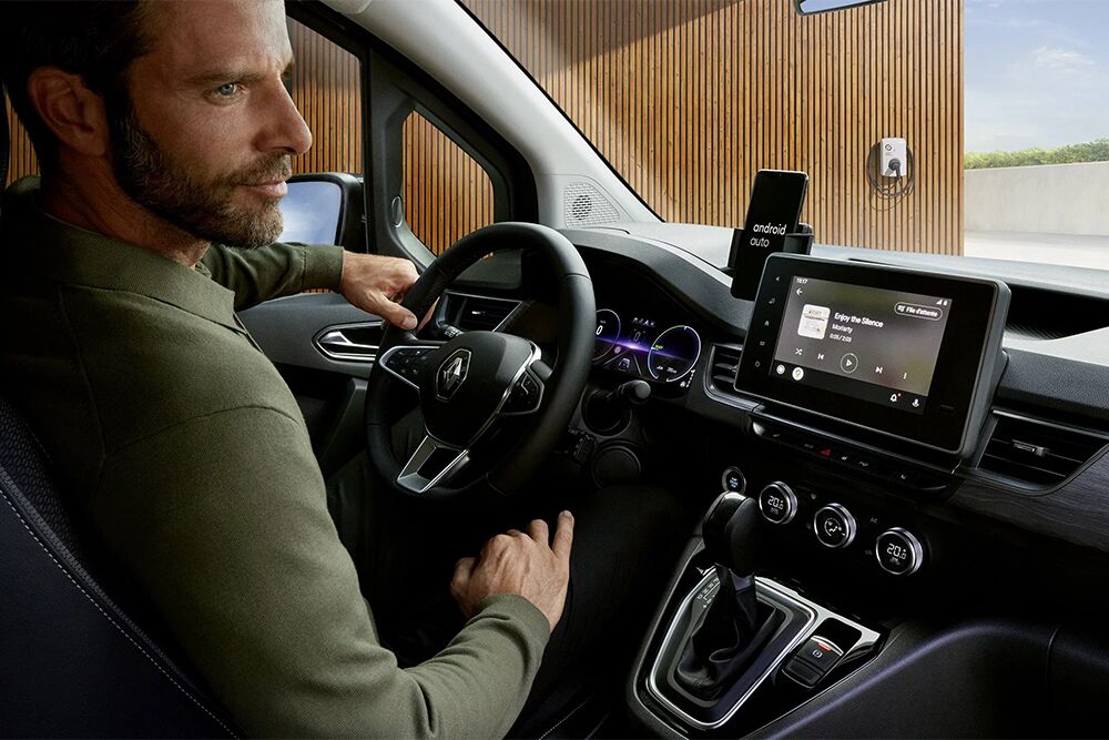 Ein Mann sitzt am Steuer des Renault Kangoo E-Tech und schaut auf den Mulitmediadisplay